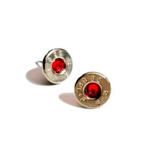 May include: A pair of silver-toned stud earrings. Each earring features a red center and is shaped like a bullet casing. The earrings are set against a white background.