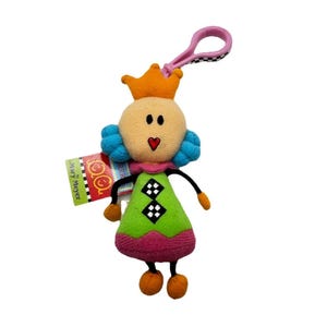 Puede incluir: Muñeca de peluche con corona, pelo azul y vestido verde con rombos blancos y negros. La muñeca tiene un clip rosa y una etiqueta que dice "Diary Meyer". La muñeca mide aproximadamente 13 cm de alto.