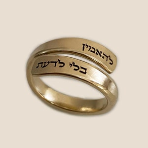 May include: A gold ring with two bands, one wrapped around the other. The top band has the Hebrew words "לְהַאֲהִיב" engraved on it, while the bottom band has the Hebrew words "כְּבִי לְדִית" engraved on it.
