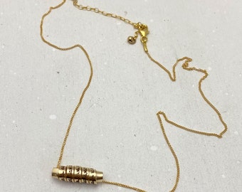 May include: A gold chain necklace with a small charm that has Hebrew writing on it.
