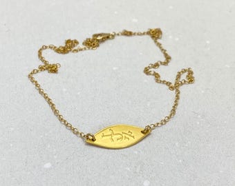 May include: A gold chain necklace with a small, oval-shaped pendant. The pendant has the Hebrew word "Chai" engraved on it.