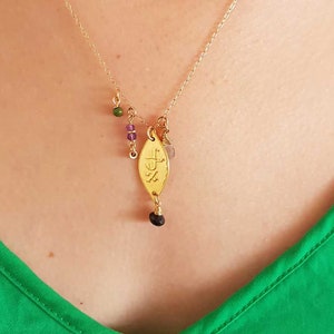 Puede incluir: Collar dorado con un colgante en forma de hoja y peque&ntilde;as cuentas de colores. El colgante tiene detalles grabados y una cuenta oscura en la parte inferior. El collar se lleva sobre una blusa verde.