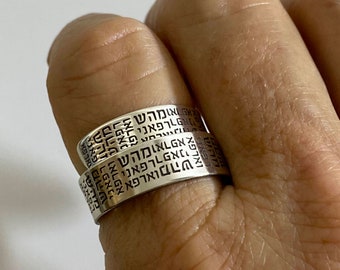May include: Two silver rings with Hebrew text engraved on them. The rings are worn on a finger.