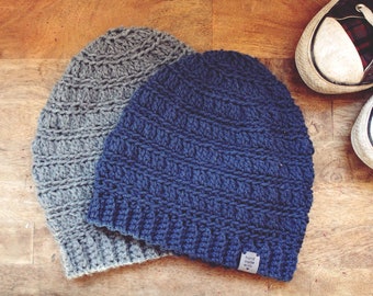May include: Two crocheted beanies, one gray and one blue, with a small tag that reads "hand made with love".