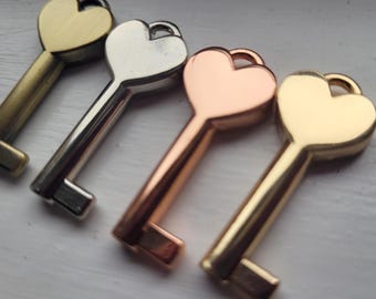 May include: Four heart-shaped keys in different metal finishes: gold, silver, rose gold, and brass. The keys are arranged in a row, with the gold key at the bottom and the brass key at the top.