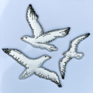 Può includere: Tre ornamenti di gabbiano bianco con accenti neri e argentati. I gabbiani sono in posizione di volo con le ali spiegate.