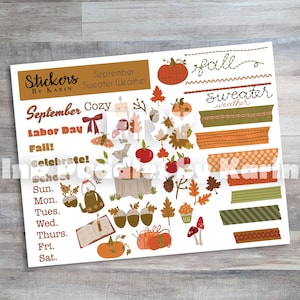 May include: A sheet of stickers with a fall theme. The stickers include pumpkins, leaves, acorns, and the words "September," "Labor Day," and "Fall." There are also decorative tape strips in various colors and patterns. The sheet is labeled "Stickers by Karin."