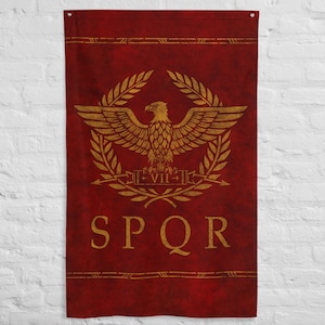 Op de afbeelding: Een rode vlag met een gouden embleem met een adelaar, lauwerkransen en de letters SPQR. De vlag heeft een verweerde, getextureerde uitstraling, met gouden randen aan de boven- en onderkant.