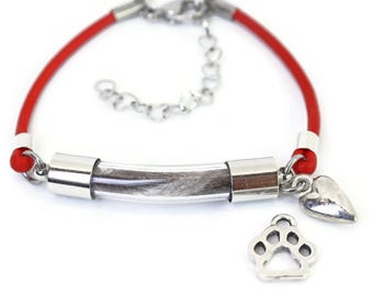 Puede incluir: Pulsera de cuero rojo con un tubo transparente que contiene pelo, detalles plateados y un dije de corazón. Incluye un dije de huella de pata. La pulsera es ajustable y tiene un cierre de langosta.