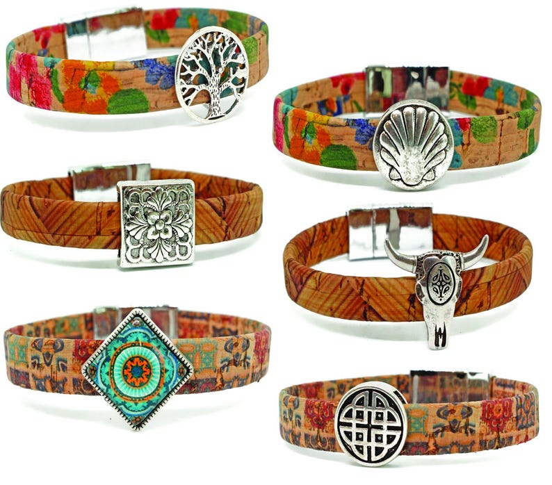 May include: A collection of cork bracelets with various silver-toned charms. The bracelets feature floral and geometric patterns in shades of red, orange, green, and brown. Charms include a tree of life, a seashell, a flower, a bull skull, a turquoise design, and a Celtic knot.