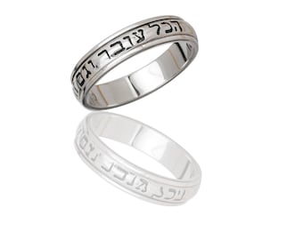 May include: A silver-colored ring with Hebrew text engraved around the band. The ring is displayed with its reflection, showcasing the intricate details of the inscription. The ring appears to be made of polished metal.