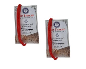 Könnte beinhalten: Zwei rote Fadenarmbänder mit Anhängern. Die Anhänger tragen die Aufschrift "ED THREAD Certificate" und "prevents bad luck & Evil-eye" mit hebräischen Texten und "JERUSALEM". Diese Armbänder dienen dem Schutz.