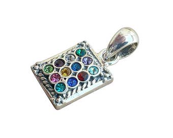 May include: A silver pendant with a square-shaped charm featuring a colorful mosaic of gemstones. The charm is surrounded by a decorative border and the pendant has a loop for attaching to a chain.