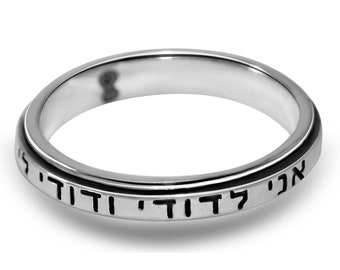 May include: A silver ring with a black band inscribed with Hebrew text. The text reads "Ani L'dodi V'dodi Li" which translates to "I am my beloved's and my beloved is mine".
