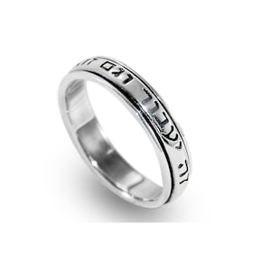 May include: A silver ring with Hebrew text inscribed around the band.