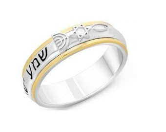 May include: A two-tone silver and gold ring featuring a Star of David, a menorah, and a Hebrew inscription. The inscription reads "Shabbat Shalom".