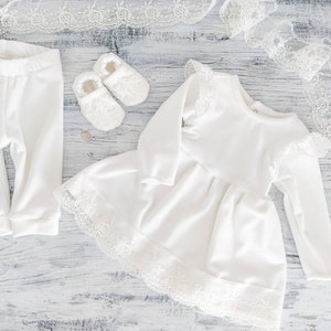 Pu&ograve; includere: Un vestitino bianco per neonata con pizzo e maniche lunghe, un paio di leggings bianchi per neonata e un paio di scarpine bianche per neonata.