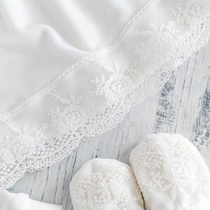 Pu&ograve; includere: Scarpine per neonato in pizzo bianco con delicato ricamo floreale. Le scarpine sono realizzate in tessuto morbido e sono perfette per un neonato.