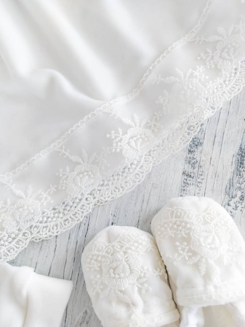 Pu&ograve; includere: Scarpine per neonato in pizzo bianco con delicato ricamo floreale. Le scarpine sono realizzate in tessuto morbido e sono perfette per un neonato.