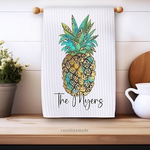 May include: White kitchen towel with a colorful pineapple design and the text "The Myers" printed on it.