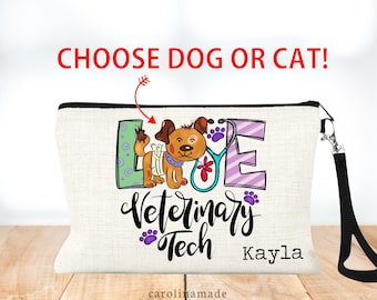 May include: A white canvas makeup bag with a black zipper and a black strap. The bag has a colorful design with the words "Love Veterinary Tech" and a cartoon dog. The name "Kayla" is written below the design.