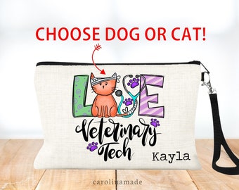May include: A white canvas makeup bag with a black zipper and a black strap. The bag has a colorful graphic of a cat wearing a bandage and the words "Love Veterinary Tech Kayla".