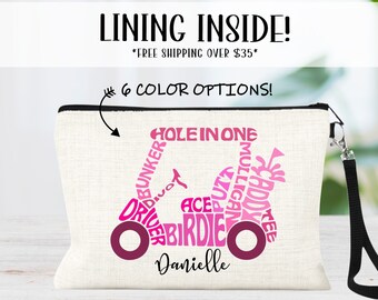 May include: A white canvas zippered pouch with a pink golf cart design made of golf terms. The cart has a personalized name, "Danielle", on the bottom.