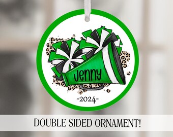 May include: Green and black cheerleading ornament with a white background. The ornament features a megaphone with the name "Jenny" and the year "2024" written on it. The ornament is surrounded by a leopard print pattern.