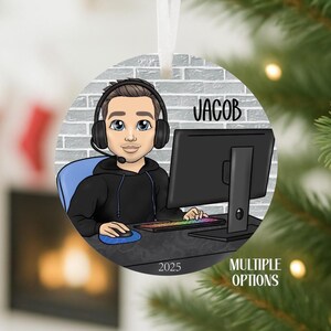 May include: Round Christmas ornament featuring a cartoon gamer with headphones, a computer, and the name "JACOB". The ornament has a white ribbon for hanging and the year "2025" is printed on the bottom. The words "MULTIPLE OPTIONS" are also printed on the ornament.