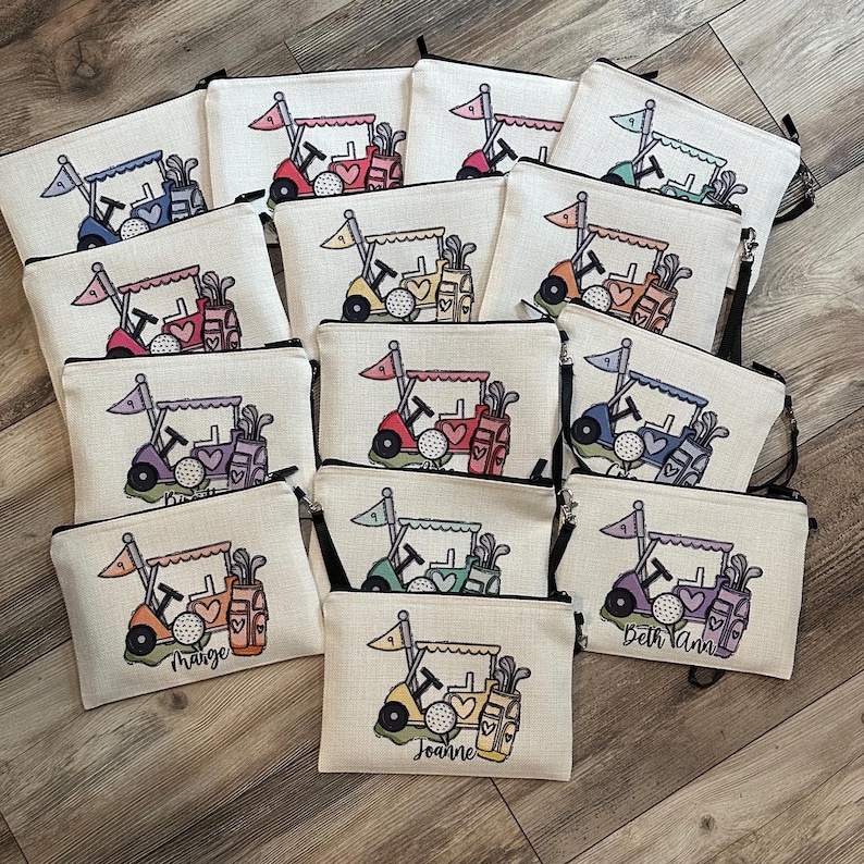 May include: A collection of golf-themed zippered pouches. Each pouch features a golf cart design with a golf ball, flag, and golf bag. The pouches are in various colors, including blue, red, green, and purple, with personalized names.
