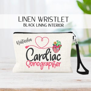 May include: Linen wristlet with black lining, featuring the name "Natasha" and the words "Cardiac Sonographer" in pink and black. A heart and anatomical heart graphic are also displayed. Includes a black wrist strap.