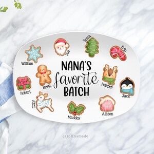 May include: Oval ceramic platter with a variety of Christmas cookie designs, including a snowflake, Santa, Christmas tree, and reindeer. The words "NANA'S favorite BATCH" are written in the center. The names of family members are written on the cookies.