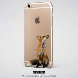 Op de afbeelding: Een gouden iPhone-hoes met een rode vos die omhoog kijkt. De vos zit op zijn achterpoten met zijn staart om zijn lichaam gewikkeld. De hoes heeft een transparante achterkant en een gouden frame.