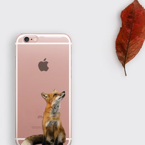 Op de afbeelding: Een roze gouden iPhone-hoesje met een transparante achterkant en een witte vos-afbeelding. De vos kijkt omhoog en heeft een bruine en oranje vacht.