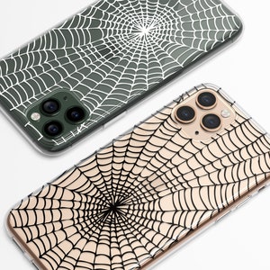 Peut inclure: Deux coques de t&eacute;l&eacute;phone transparentes avec un motif de toile d'araign&eacute;e. Une coque a une toile d'araign&eacute;e blanche sur un fond vert fonc&eacute;. L'autre coque a une toile d'araign&eacute;e noire sur un fond beige clair.