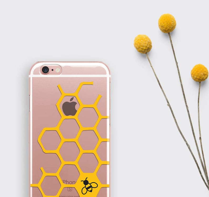 May include: A clear phone case with a honeycomb pattern and a small bee graphic. The case is pink and the honeycomb is yellow. The text "Phone" is visible on the case.