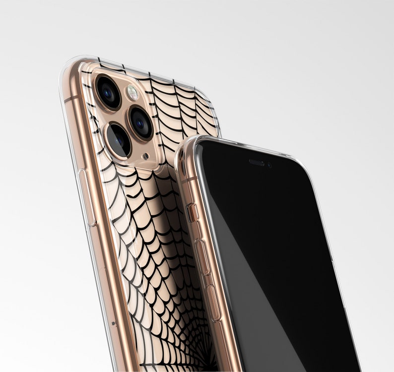 Peut inclure: Une coque de t&eacute;l&eacute;phone transparente avec un motif de toile d'araign&eacute;e noire. La coque est pr&eacute;sent&eacute;e sur un iPhone dor&eacute;.
