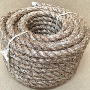 May include: A coil of natural fiber rope, likely made of sisal or hemp, in a light brown color. The rope is tightly wound and appears to be strong and durable.