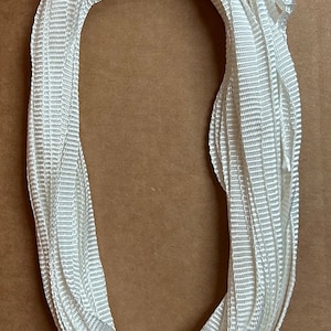 May include: A white nylon rope coiled in a circle. The rope is about 1 inch wide and has a textured surface.