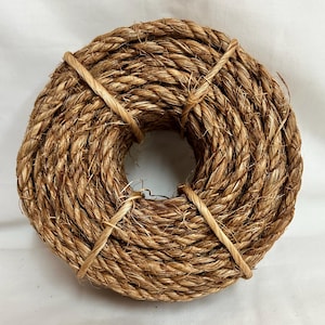 May include: A coil of natural brown sisal rope. The rope is tightly wound and tied with a brown twine.