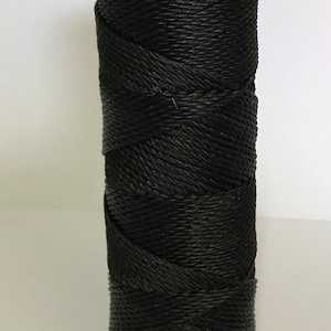 May include: A spool of black string, wound tightly and ready for use in crafts or other projects.