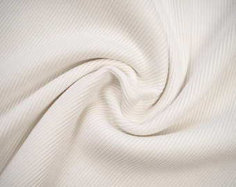 May include: White ribbed fabric with a soft, smooth texture. The fabric is folded and draped, creating a smooth, flowing look.