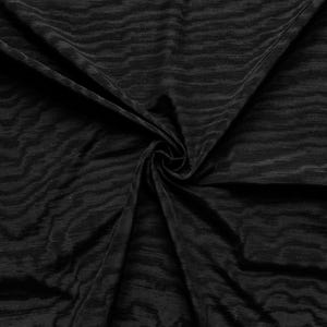 Może przedstawiać: Czarna tkanina o teksturowanym, falistym wzorze. Materiał jest udrapowany i zakręcony, tworząc cienie i światła. Materiał wydaje się miękki i płynny, odpowiedni do odzieży lub wystroju wnętrz.