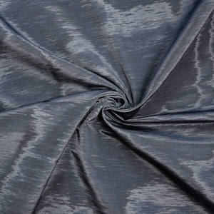 May include: A close-up of a dark gray fabric with a subtle shimmer. The fabric is wrinkled and folded, creating a textured surface.