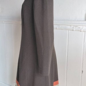 May include: A brown dress with a long sleeve and a white and orange stripe design at the hem.