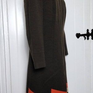 May include: A brown dress with a geometric pattern in orange and cream on the hem.