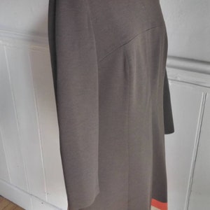 May include: A brown dress with long sleeves and a white and orange stripe at the hem.