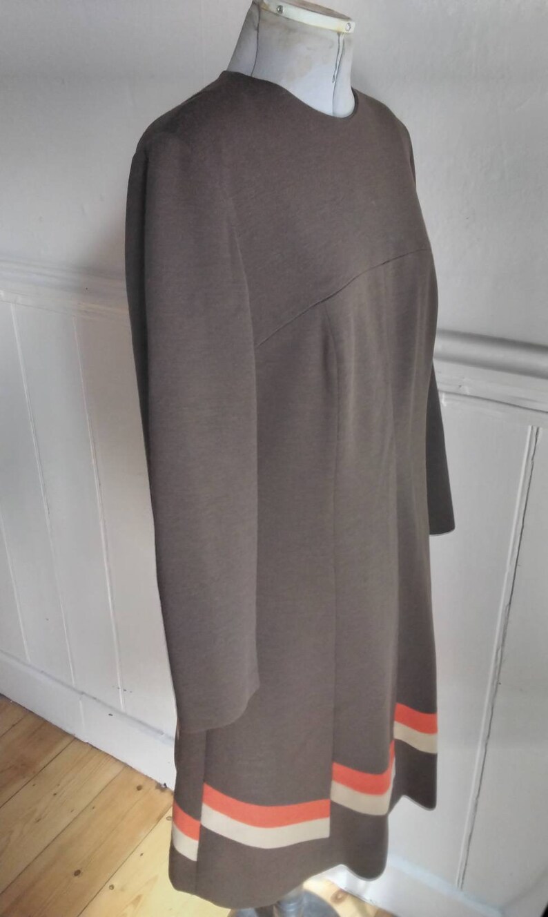 May include: A brown dress with long sleeves and a white and orange stripe at the hem.