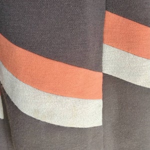 May include: A brown skirt with orange and beige stripes. The skirt is made of a woven fabric.