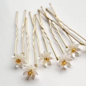 May include: Set of ten gold hair pins with white flower accents and a yellow center bead.